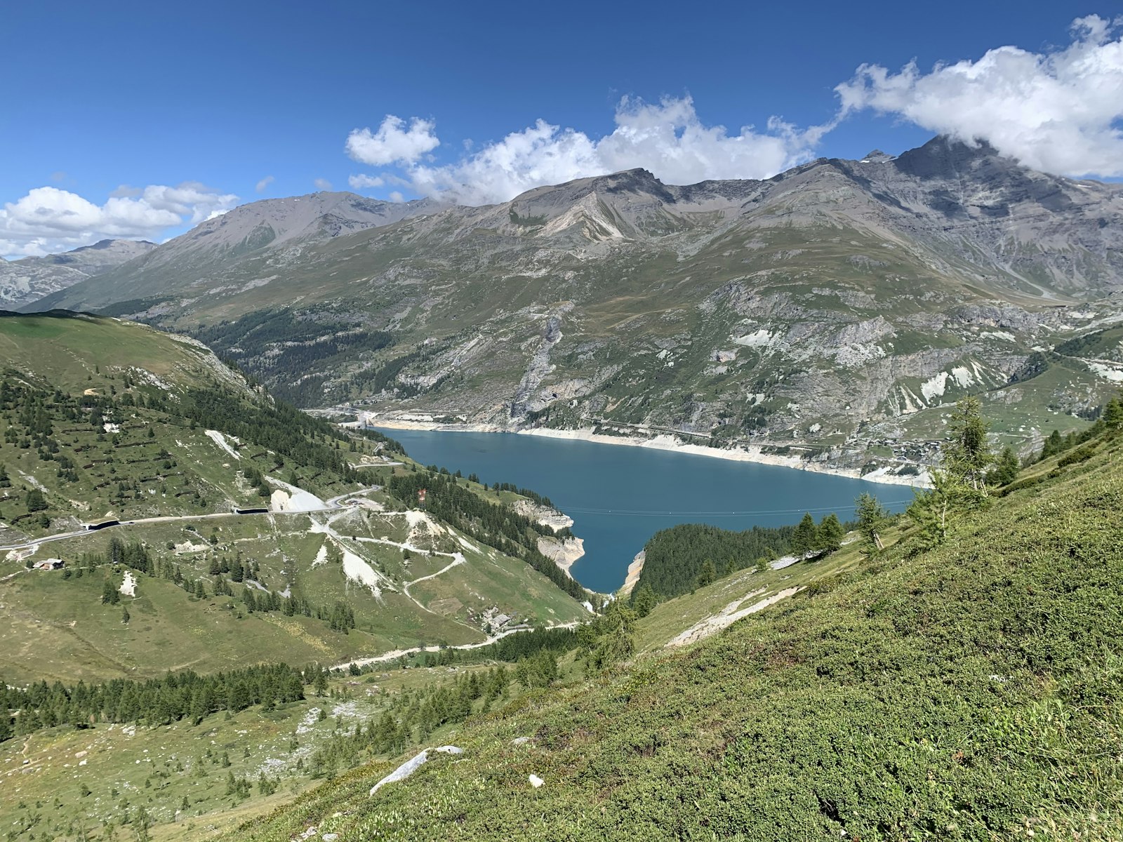 Turquoise Lac du Chevril and green mountain slopes near Tignes in summer